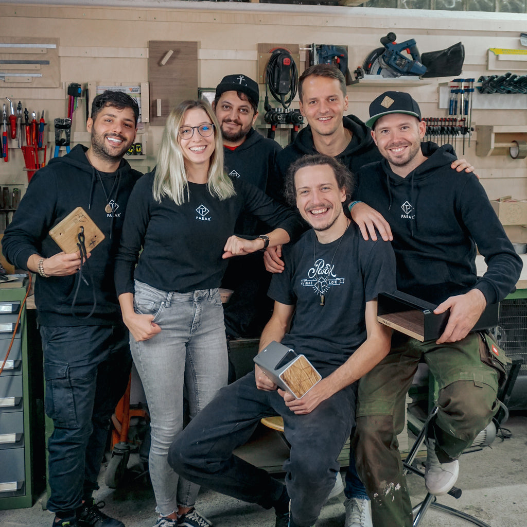 Teamfoto von schwarz gekleideten PARAX Mitarbeiter*innen, die mehrere Fahrrad Wandhalterungen in den Händen haben