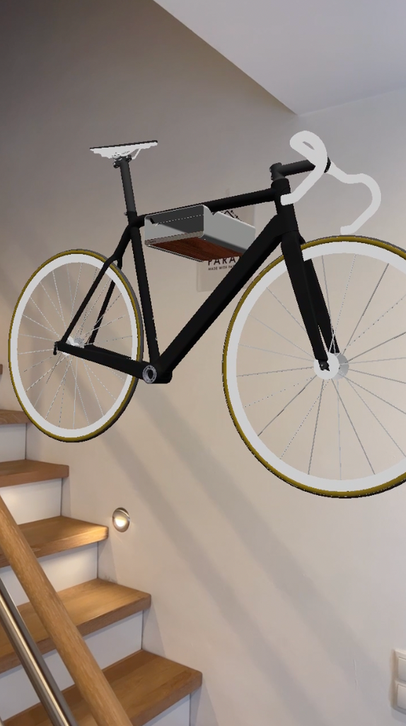 Schwarzes Augmented Reality Fahrrad auf schwarzer Fahrrad Wandhalterung D-RACK vor weißer Wand und über Holztreppe