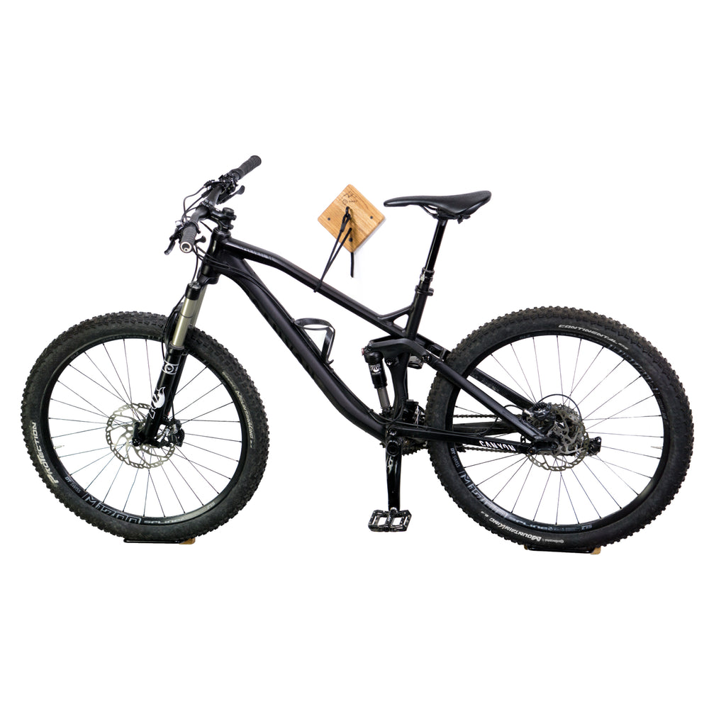 Fahrrad Wandhalterung U-RACK aus Holz und schwarzem Stahl mit schwarzem Fahrrad vor weißer Wand