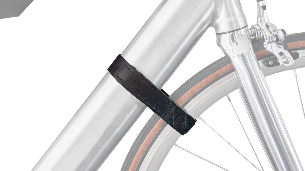 Silbernes Vorderrrad eines Fahrrads mit schwarzem Lederband, das um Rahmen und Vorderrad gebunden ist