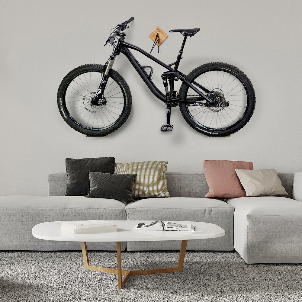 Fahrrad Wandhalterung U-RACK aus Holz mit schwarzem Fahrrad an grauer Wand über grauem Sofa mit bunten Sofakissen